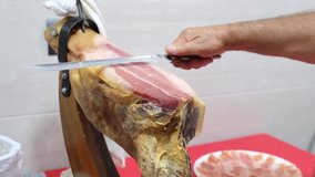 Senior man cutting iberian ham with a ham knife. Spanish gastronomy concept.