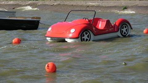 Plastic  boats in shape of cars on sea  waves near coast

