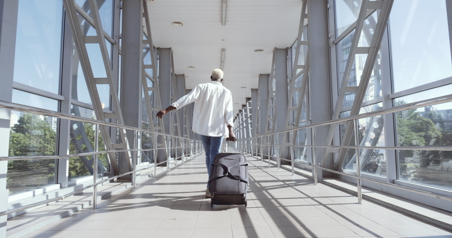 African guy stylish trendy mixed race model man carrying suitcase luggage, dancing alone in airport terminal, moving to boarding train, enjoying travel trip abroad, celebrating vacation, holiday maker Royalty-Free Stock Footage #1060791478