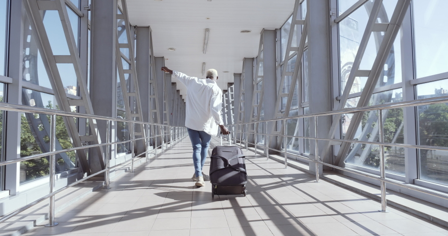 African guy stylish trendy mixed race model man carrying suitcase luggage, dancing alone in airport terminal, moving to boarding train, enjoying travel trip abroad, celebrating vacation, holiday maker | Shutterstock HD Video #1060791478