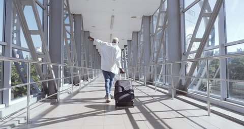African guy stylish trendy mixed race model man carrying suitcase luggage, dancing alone in airport terminal, moving to boarding train, enjoying travel trip abroad, celebrating vacation, holiday maker