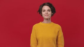 Young fun woman 20s in yellow sweater get video call using mobile cellphone doing selfie videoconference conducting pleasant conversation isolated on red background in studio. People lifestyle concept