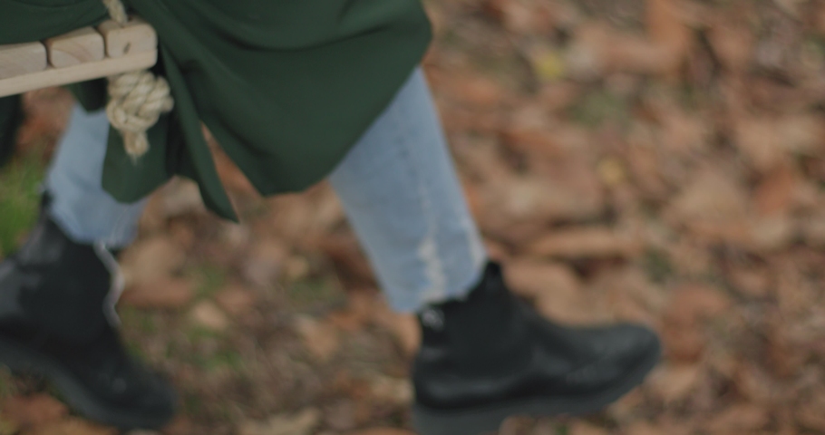 Young woman taking out from her bag a diary book and hold it tight in her arms on a swing, in autumn. slow motion