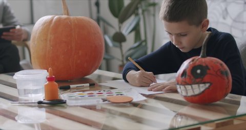 Kid drawing halloween holiday decoration with pencils. Young mother working at home. Social media campaign for pandemic coronavirus covid-19 prevention.
