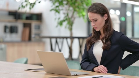 Businesswoman with Back Pain using Laptop at Work 