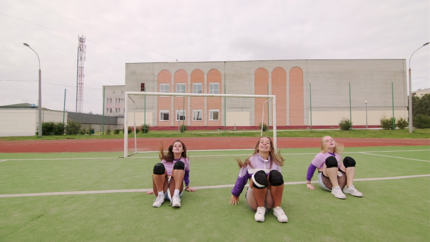 Group of young cheerful women  with long hair in shorts dancing booty dance on the stadium.