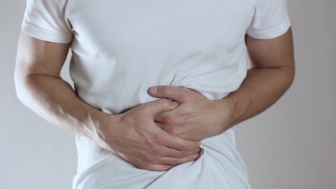 The man has a stomach ache. Close up. Isolated on a gray background.