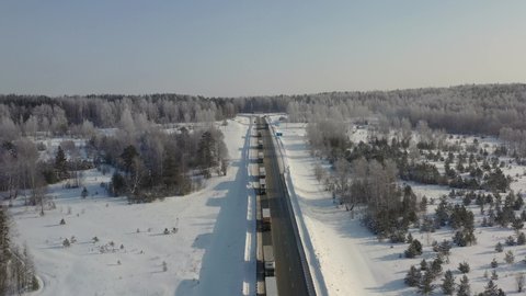 AERIAL. Top view to the truck's column driving on the snow road in winter time. 