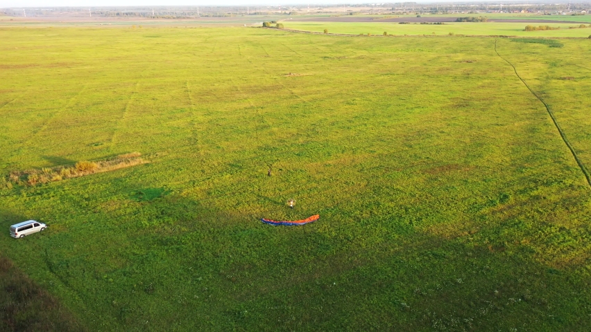 Motor paraglider starts to take off on the field, but the pilot makes a mistake when taking off and lifting the wing and the wing descends to the grass. Aerial view. Royalty-Free Stock Footage #1060802146