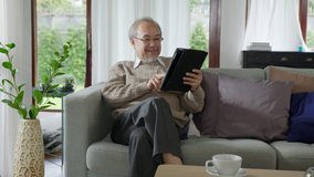 Candid of old asian retired man using tablet computer to transfer money online or financial payment and read text, smile or laugh with happy and positive. Senior asian with digital technology concept - Powered by Shutterstock - Get 15% off with code: PIKWIZARD15