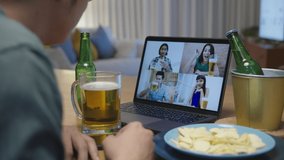 Close up : Attractive young happy asian man enjoy relax night party event online celebration festive with friends at home clinking beer with glass and bottle toasting drinking via video call.