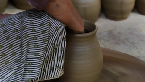 Close-up of a woman potters rotate a wheel with her foot and making a beautiful clay pot with her hands at pottery manufacture in the Old Town Hoi An, Vietnam