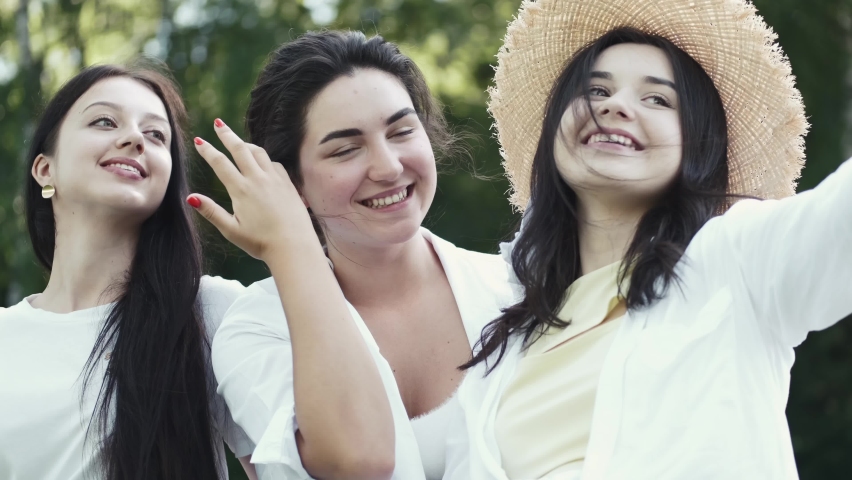 Friends party concept. Photo of happy European women taking selfie photo and laughing. The adies are having fun together outdoors.