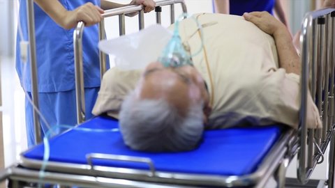 Emergency Department: Group of Doctors, Nurses and Surgeons Move Seriously senior Patient Lying on a Stretcher Through Hospital Corridors. Medical Staff in a Hurry Move Patient into Operating Theater.