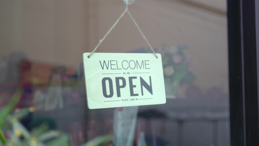 Asian woman wear mask turning Welcome we are open sign on fronton glass door cafe. Reopening activity after COVID-19, ended the lockdown and quarantine. Restarting again and keep forward concept. | Shutterstock HD Video #1060807948