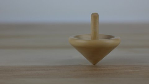 Wooden spinning top moving on wooden surface, close up
