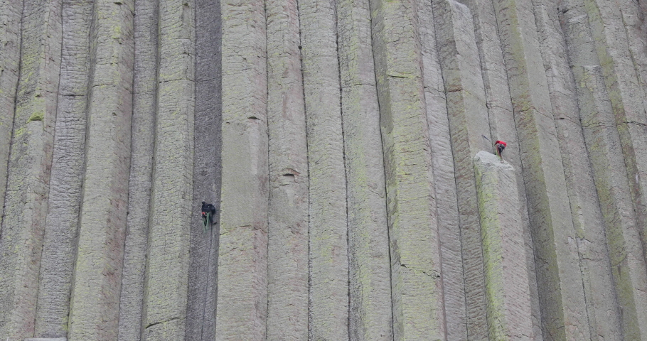 Two rock climbers Devils Tower high steep dangerous 4K. 1,267 feet tall igneous rock tower in Black Hills of South Dakota and Wyoming. United States National Monument. Recreation, tourism, vacation.