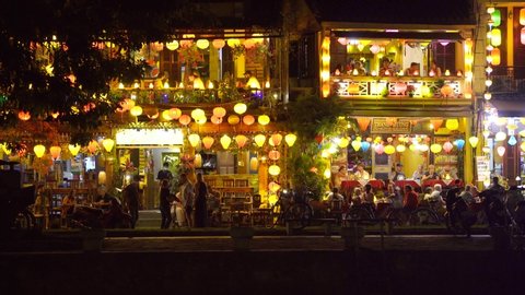 Hoi An, Vietnam - march 15, 2020 : European tourists rest in street restaurant near river in Hoi An town at night. Hoi An is city near Da Nang in Vietnam and famous for its well-preserved old town