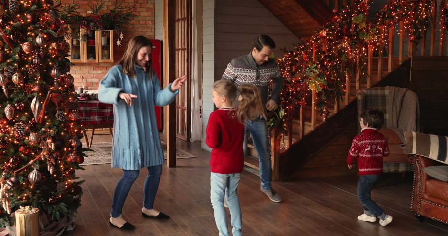 Full length happy family with little children celebrate Christmas Eve festive time listen funky music dancing at beautifully decorated twinkle lights and xmas tree house. Holiday mood, hobby concept Royalty-Free Stock Footage #1060811299