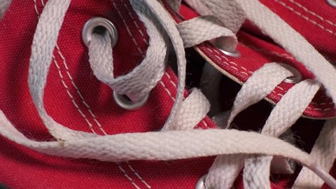 Close-up of rotating pair of red used sneakers  with white laces. Sport shoes, youth fashion concept.