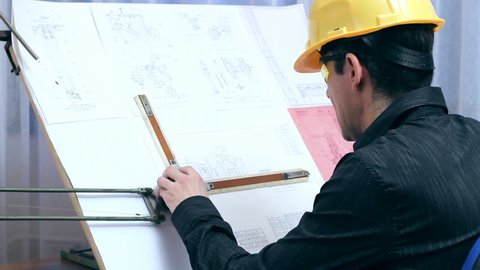 The engineer drawing on a drawing board and measuring dimensions of metal component with a divider caliper.  Sequence of three clips. Man Draws a Technical drawing in an office. Stock Video