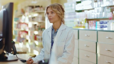 Slow motion woman pharmacist serving a customer in a drugstore. Conversation pharmaceutical client. Seller commercial health care buyer uniform.