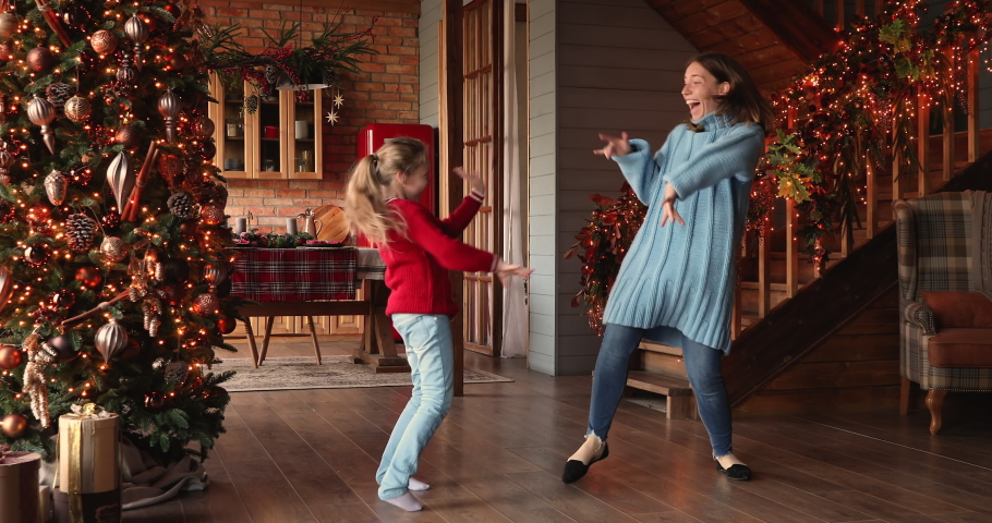 Family listen funky music spend time in decorated glowing lights house hall, mom little daughter fooling around dancing at home enjoy winter holidays celebrate Christmas, relish New Year party concept Royalty-Free Stock Footage #1060819141