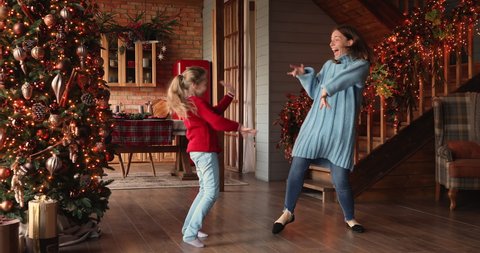 Family listen funky music spend time in decorated glowing lights house hall, mom little daughter fooling around dancing at home enjoy winter holidays celebrate Christmas, relish New Year party concept