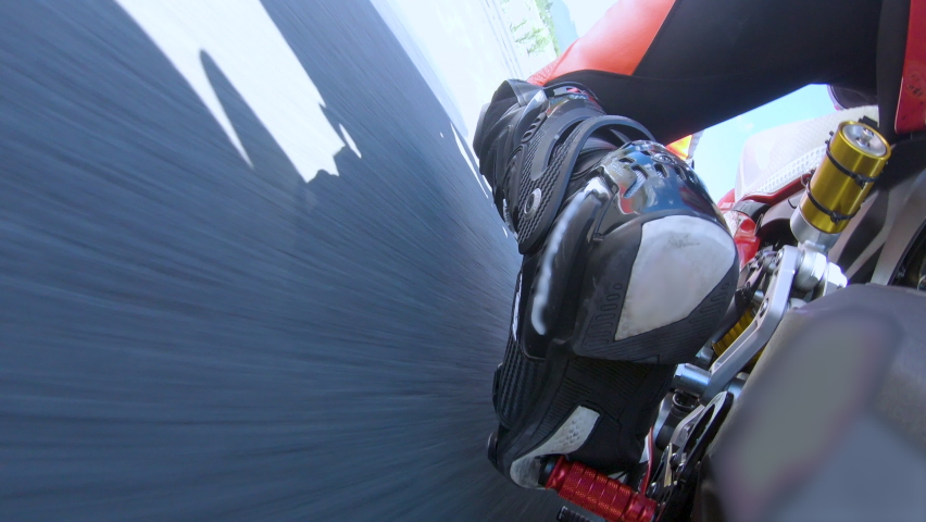 Close up shot of motor riders knee bending through bends on the moto race track.