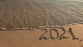 The inscription 2021 in the sand is washed away by the sea wave. Concept of the new 2021. Seashore at sunset.