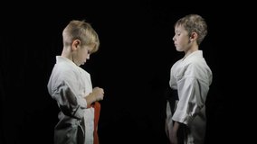 In karategi, boys train punches and blocks on a black background