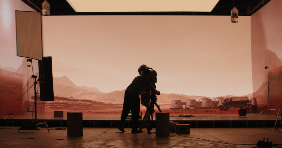 Behind the scenes shot of virtual production stage with huge LED screens, cinematorgapher shooting Mars scene. Future of movie production Royalty-Free Stock Footage #1060829710