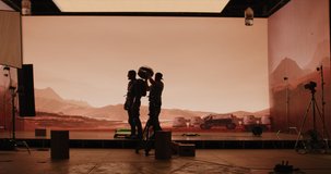 Behind the scenes shot of virtual production stage with huge LED screens, cinematorgapher shooting Mars scene. Future of movie production