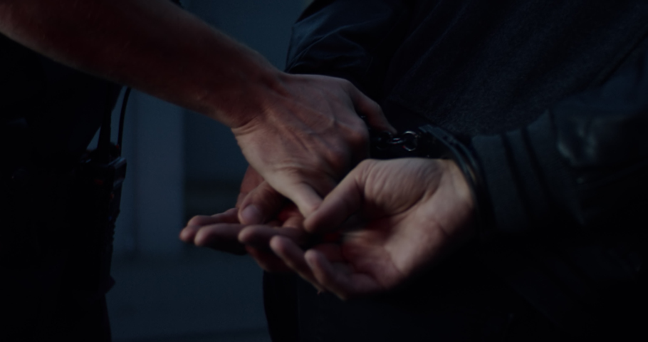 CU on hands, man being handcuffed near unmarked police vehicle in the street. Shot on RED Dragon with 2x Anamorphic lens Royalty-Free Stock Footage #1060829716