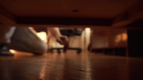 Man Looking For Something Under The Bed. The hand gropes for an object