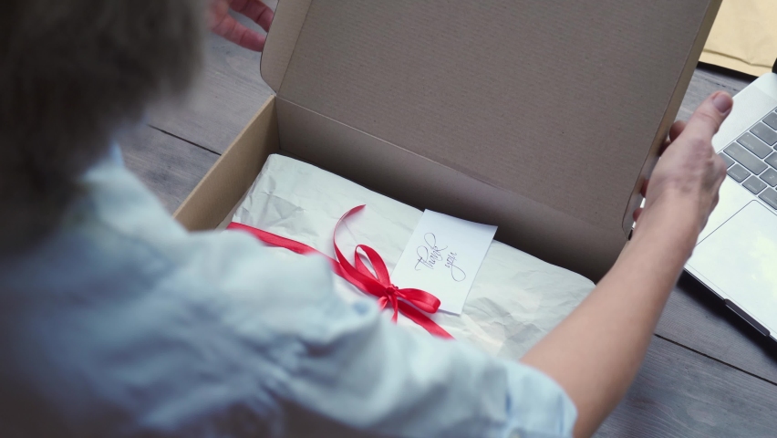 Close up over shoulder view of old female online store small business owner worker packing package post shipping ecommerce retail order in box preparing delivery parcel on table. Dropshipping service. Royalty-Free Stock Footage #1060830655