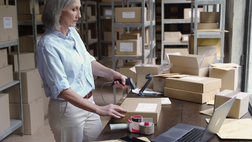 Middle aged older female online store small business owner, warehouse worker, merchant packing package shipping ecommerce retail order in box preparing delivery parcel on table. Dropshipping service. | Shutterstock HD Video #1060830667
