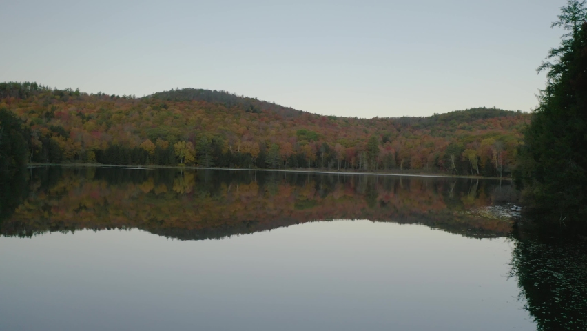 Reflection of fall foliage on pond in Vermont, New England - 4K Drone