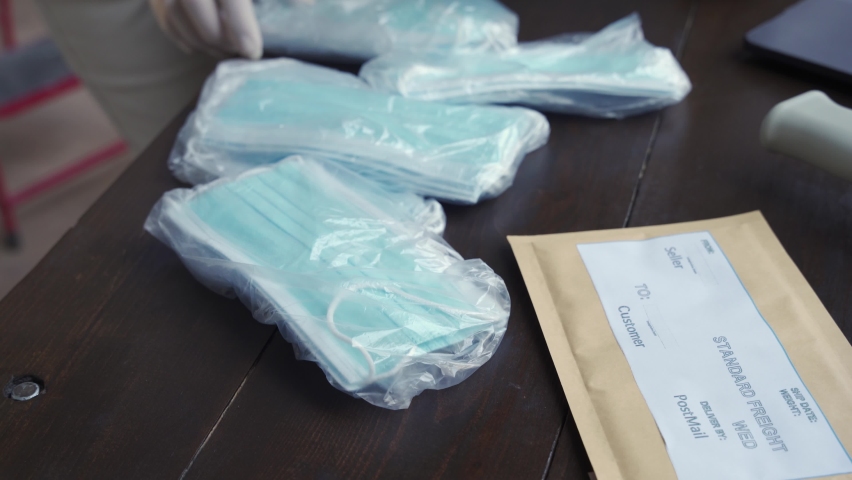 Female volunteer wearing gloves packing medical face masks in shipping delivery charitable donations box, close up view. Covid 19 coronavirus donating aid, distribution and volunteering supply concept Royalty-Free Stock Footage #1060832179