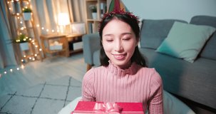 asian young woman wearing birthday hat has video chat online by laptop while celebrating and giving present box for her friend