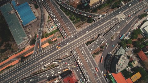 Slow motion of cross highway top down at Philippines cityscape aerial. Cars, buses, vans, trucks ride at traffic roadway of Manila city. Urban scenery with buildings, skyscrapers, cottages at road