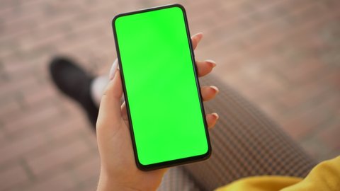 Handheld Camera: Point of View of Woman at street Using Phone With Green Mock-up Screen Chroma Key Surfing Internet Watching Content Videos Blogs Tapping on Screen