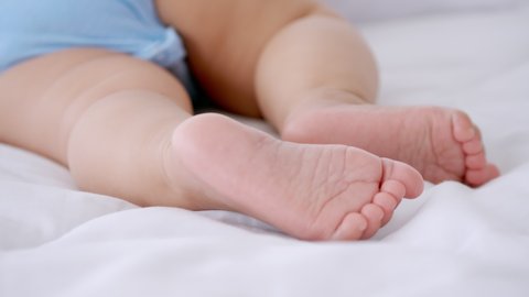 Feet of newborn baby lying in bed at home.