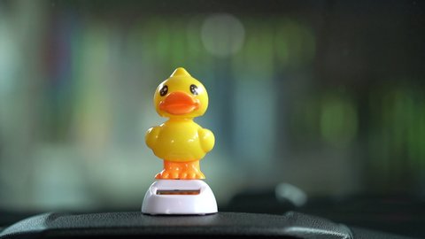 Yellow Duckling doll dancing on dashboard in a car.