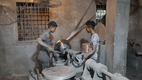 DHAKA, BANGLADESH - OCTOBER 10, 2020: In a toxic, dangerous and non compliant sweatshop, underaged workers are engaged in child labor not respecting occupational health and safety rules in a factory