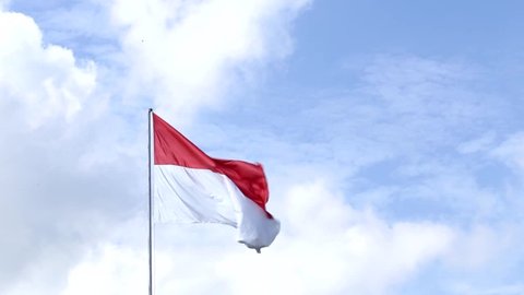 Indonesia Flag flying in the wind outdoors with Blue sky behind - Indonesian flag on flagpole.