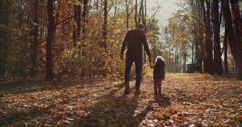 Father and children walking in the park and enjoying the beautiful autumn nature. Happy family on autumn walk. Slow motion
