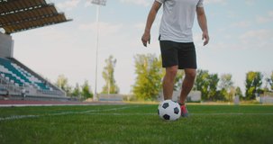 A soccer player at the stadium demonstrates dribbling with a soccer ball while leading a sword while running. Excellent skill of a football player and ball control