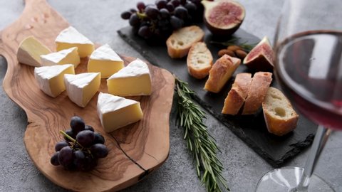 Camembert or brie cheese with glass of red wine, grapes, baguette and figs. Cheese platter, appetizer snack table