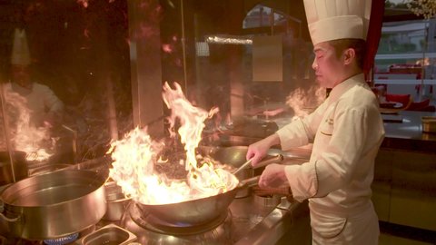 Abu Dhabi / UAE - 15 November 2018: Chef Cooking with Flames / Fire in Wok in the Kitchen, Slow Motion